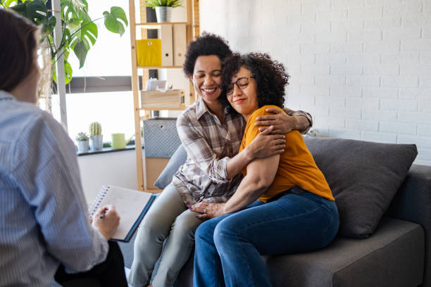 Lesbian couple getting relationship counseling by therapist Lesbian couple embracing during relationship counseling. It seems that they solved a marriage problem. lesbian couple embracing stock pictures, royalty-free photos & images