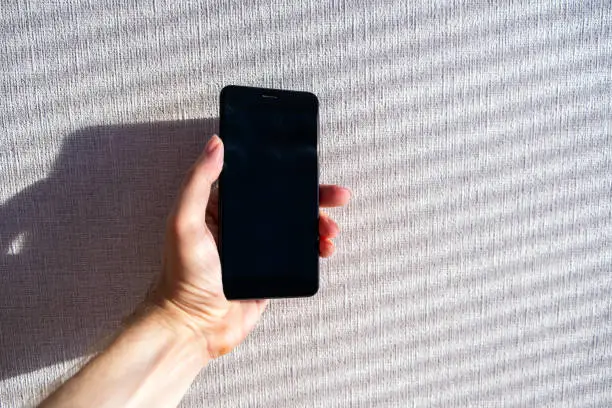 Person hold a Mobile Phone on the White Wall Background closeup