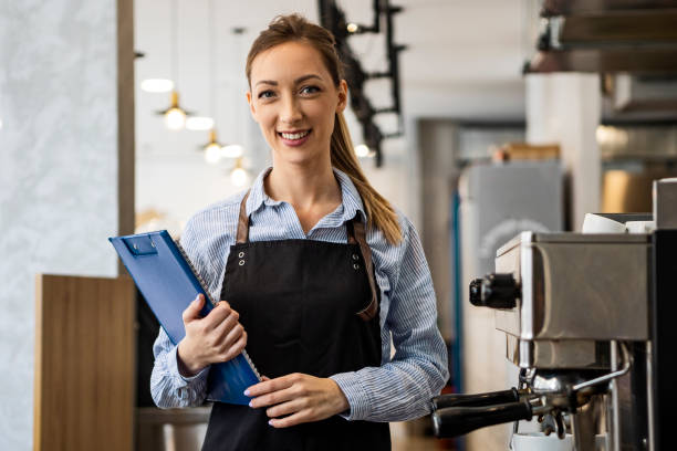 istock Smiling coffee shop owner standing on her workplace looking at camera 1388566539