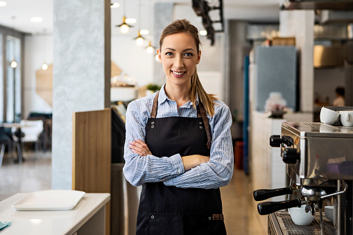 Smiling coffee shop owner standing on her workplace