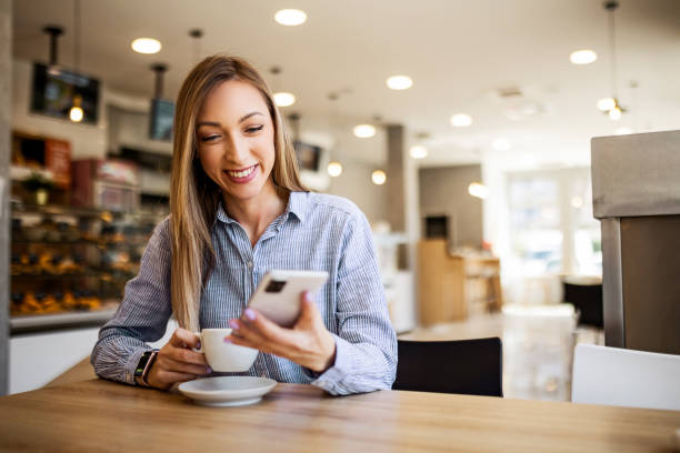 istock Young woman at restaurant drinking coffee and using phone 1388567103