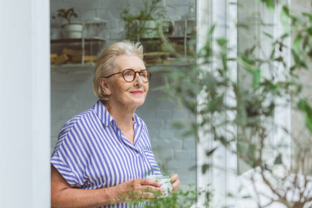 istock Senior woman having coffee at window 1388570765