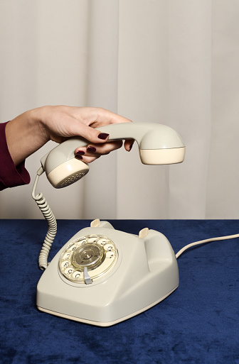 Female hand holding handset of vintage telephone