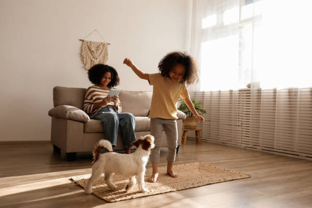 Teenaged girl and her little sister at home. Two beautiful black girls of different age playing with their adorable wire haired Jack Russel terrier puppy at home. Loving sisters with rough coated pup having fun. Background, close up, copy space. wire haired stock pictures, royalty-free photos & images