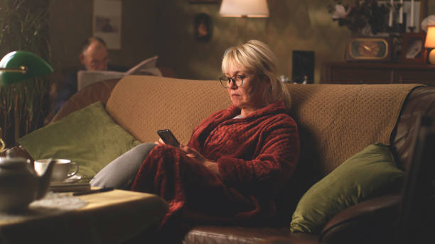 istock Sad senior female with smartphone resting on couch 1388577382