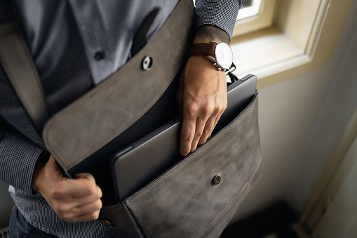 Unrecognizable fashionable Caucasian businessman take out his digital tablet/laptop from leather briefcase