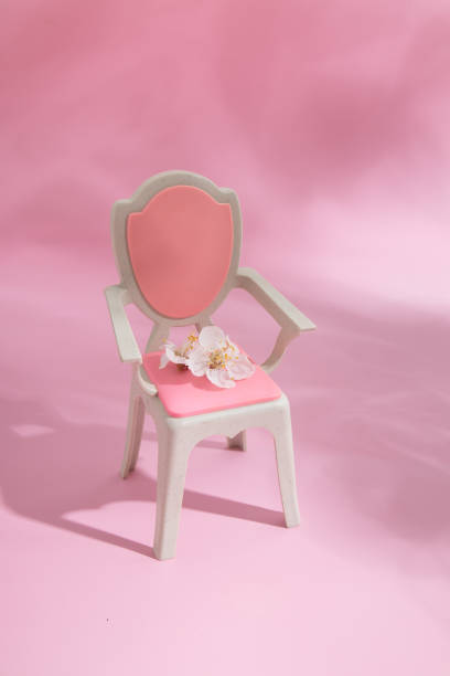 istock Abstract composition spring still life puppet chair with white flower on pink background 1388579212