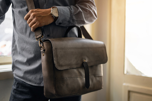 Portrait of fashionable unrecognizable businessman with leather briefcase