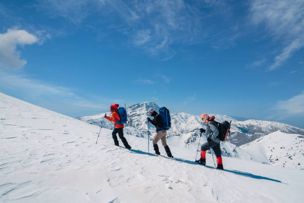 successful mountain climber team is climbing in a row on the ridge of the  high altitude snowy mountain summit in winter - achievement mature adult adult mountain range imagens e fotografias de stock