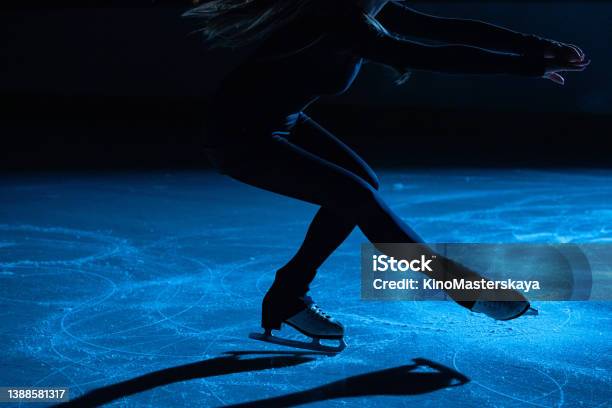Figure Skating Lady Is Wearing Black Sportswear Is Skating On Ice Rink Training At Night In The Rays Of Blue Light Young Woman Preparing To Competition Training Rotation And Slides Skills Close Up Stock Photo - Download Image Now