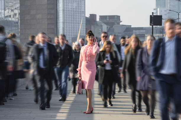 istock Mature female CEO using phone while crossing London Bridge 1388581572