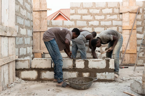 Accra, Ghana - 7 Februar 2022:  Bricklayers pull up a wall on a construction site of a residential building