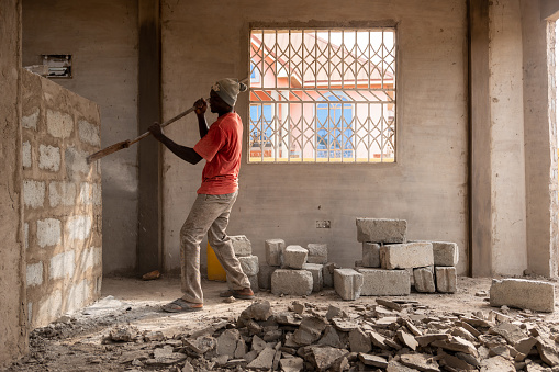 Bricklayer working in construction site of a brick wall. Bricklayer putting down another row of bricks in site. Worker puts a brick wall