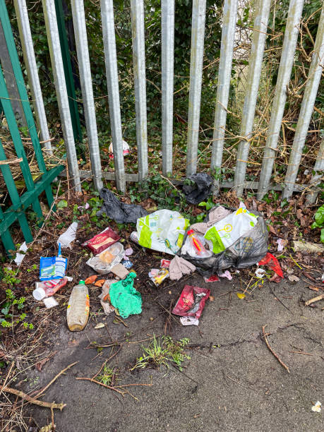 bild eines müllhaufens, der auf dem bürgersteig neben einem metallzaun zurückgelassen wurde, die umgebung übersät, blick in den hohen winkel, fokus auf den vordergrund - garbage dump vertical outdoors nobody stock-fotos und bilder