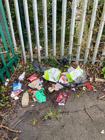Frome, Somerset, England - March 18, 2022: Stock photo showing pile of rubbish on tarmacked pavement of junk food packaging discarded by teenagers.