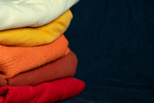 istock A stack of multi-colored fabric in warm colors. Background with folded clothes in red and yellow tones with empty space for information. T-shirts of different colors 1388586055