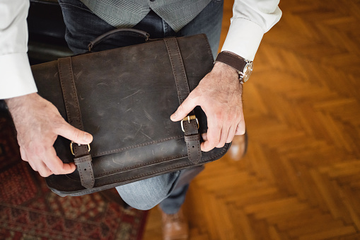 High angle view of unrecognizable modern businessman opening leather briefcase