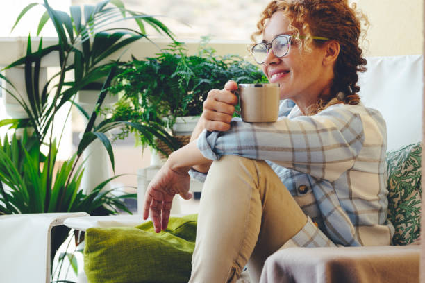 istock Smiling Mature Woman Holding Coffee Cup Sitting On Sofa 1388589846