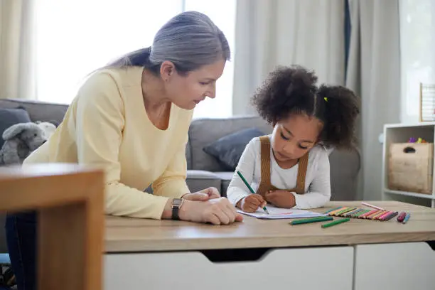 Photo of Shot of a little girl drawing in a psychologists office