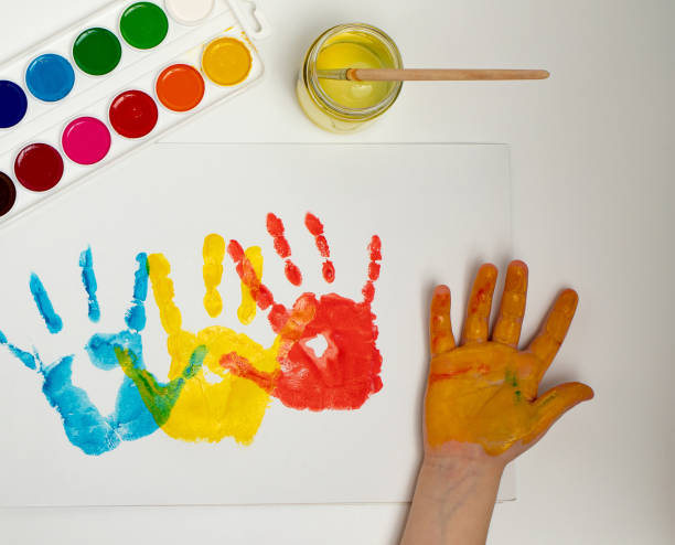 istock Close-up hand, colored palm prints on white paper, creative creativity concept, fine motor skills, patience 1388595792