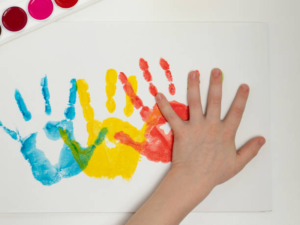 istock Close-up hand, colored palm prints on white paper, creative creativity concept, fine motor skills, patience and perseverance 1388595798