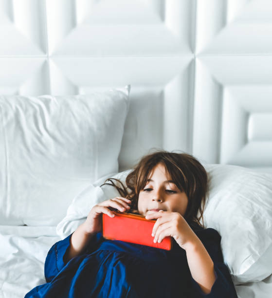 istock Little girl laying down in a bed using a cellphone and relaxing 1388596100