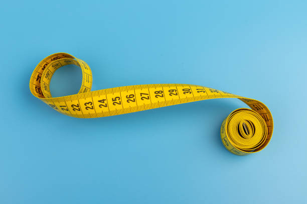 istock Yellow spiral tape measure on blue background. Centimeter. Space for text. 1388596309