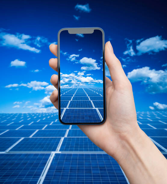 Hand holds mobile phone on solar panels stock photo