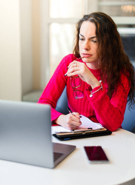 donna che usa il laptop con un volto serio o preoccupato. forse problemi sul lavoro, con la telegrafia o le finanze - wireless telegraphy foto e immagini stock