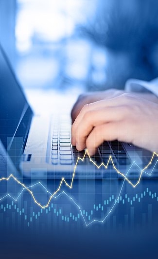 close-up hands working on a computer keyboard. Curves and graphs symbolizing business, finance, economic growth or global crisis or business success