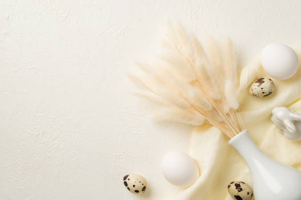 istock Top view photo of easter decorations white vase with lagurus flowers ceramic easter bunny quail eggs and cloth on isolated white background with empty space 1388602364