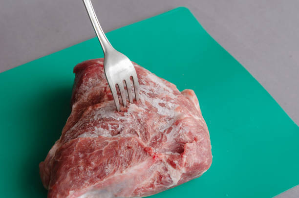 istock Frozen d-rump with a fork stuck on a gray-green background. 1388603449