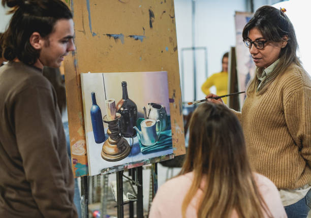 istock Mature latin teacher working with students inside art class room at school 1388604451