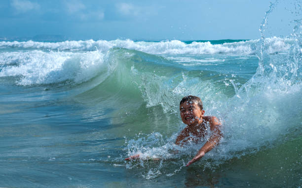 A children play with big waves of the sea. Summer family vacation concept A children play with big waves of the sea. Summer family vacation concept wave jumping stock pictures, royalty-free photos & images