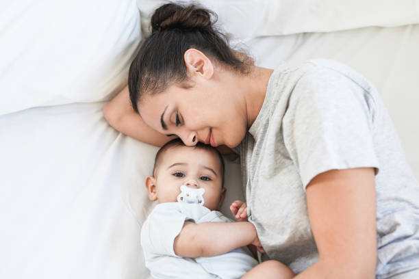 istock Young mother having tender moment with baby while lying on bed at home 1388605747