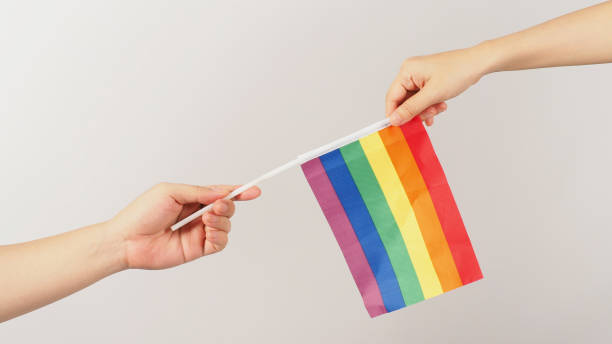 istock Two hands send and recive a rainbow flag on white background. LGBT CONCEPT. 1388607262