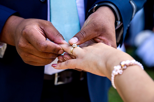 Groom putting ring on bride`s finger closeup of hands and ring