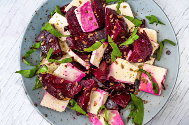 Tofu with baked red beetroot, flaxseed and leaf on plate, closeup stock photo