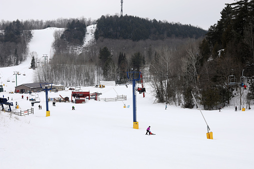 Hidden Valley Highlands Ski Area in Muskoka near Huntsville, Ontario during March Break in March 2022. Staycation in Ontario, Canada. Skiing and snowboarding in Ontario. Canadian mountains. Active Spring Break in Canada. Skiers and snowboarding enjoying the ride in Muskoka mountains