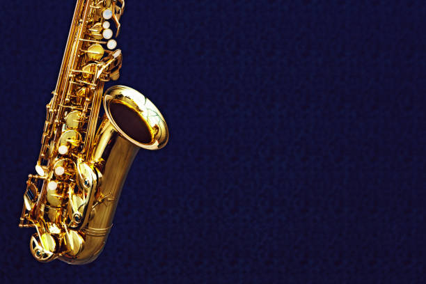 saxofón alto brillante sobre un fondo azul oscuro sutilmente estampado - light jazz fotografías e imágenes de stock