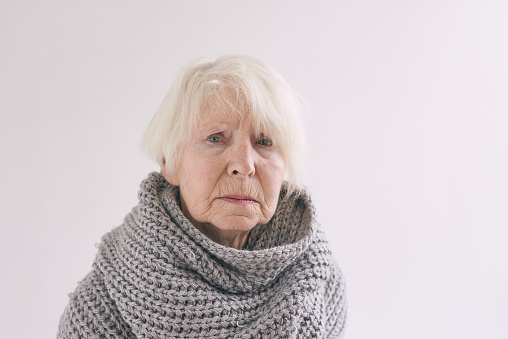 senior woman in scarf freezing cold at home. Health care, crisis, oldness concept