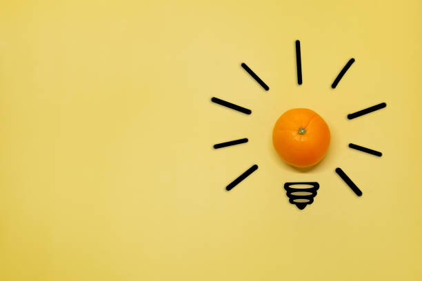 istock Creative thinking ideas and innovation concept. A ball of orange with a light bulb symbol on a yellow background. Time for a healthy diet. 1388612097