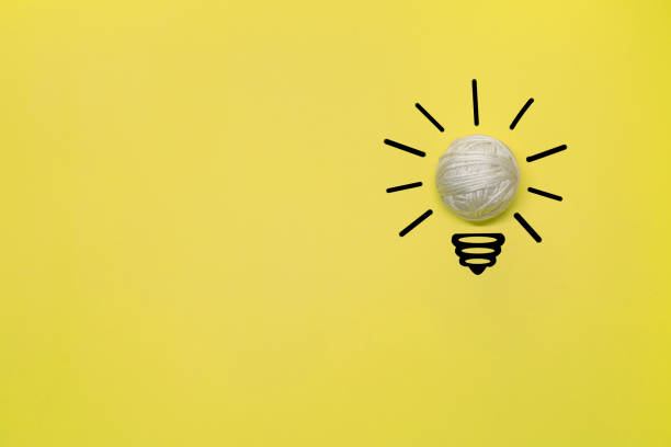 istock Creative thinking ideas and innovation concept. A ball of white threads with a light bulb symbol on a yellow background 1388612101