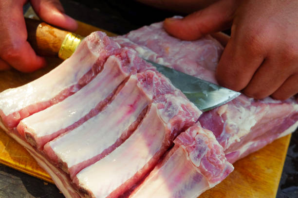 Butcher cuts fresh meat with a knife. Pork ribs with meat.