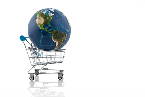 Shopping around the world. Little planet Earth and shopping cart on white background. \nVisual references from NASA (https://visibleearth.nasa.gov/images/74117/august-blue-marble-next-generation).