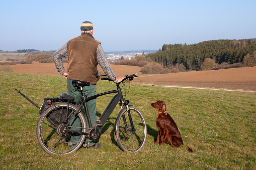 On a glorious spring morning, a cyclist and his Irish Setter dog take a break and enjoy the view of the twin town of Villingen-Schwenningen in southwest Baden-Württemberg.