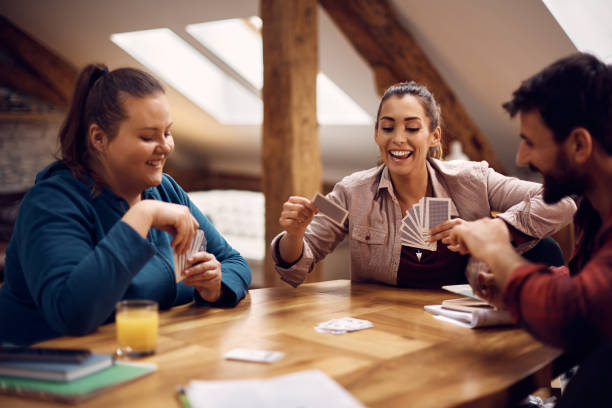 istock Happy woman having fun while playing poker with her roommates at home. 1388616749