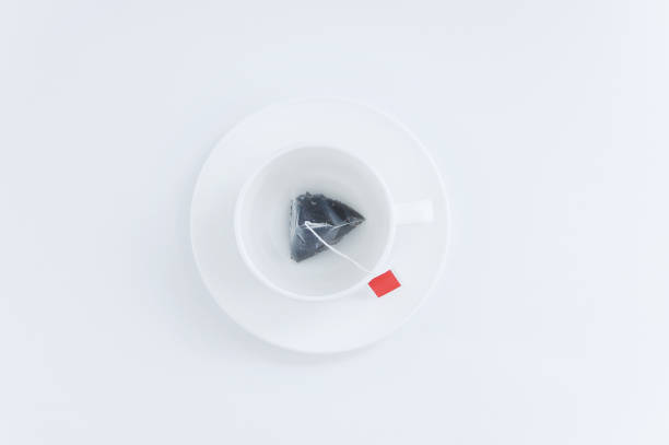 Studio shot of a teacup with two teabags, extra strong tea. Food and drink backdrop showing a mug of hot beverage served. It can be used as a conceptual image for breakfast time, having a tea break or for any industry working with food and beverage.