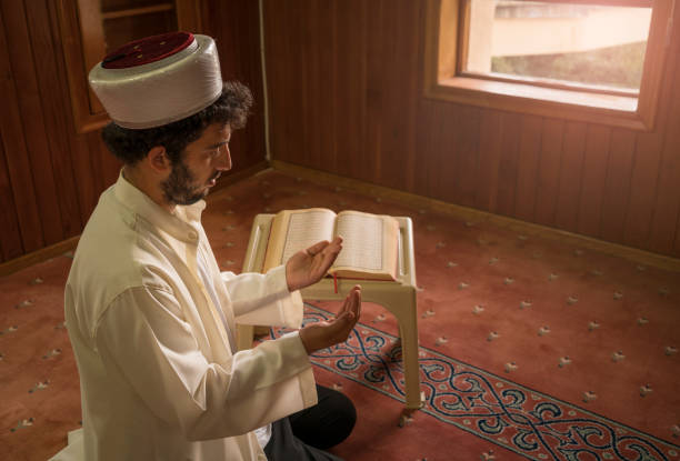 istock Imam prays to Allah with open hands in mosque. 1388619318