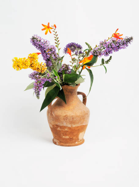 Mixed cut flowers in old terracotta vase.